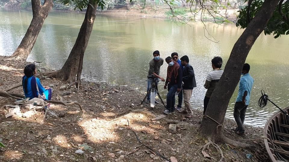 জলাশয়ের পাড়ে প্রাকৃতিক পরিবেশে ক্যামেরা ট্রাইপড ও বুম মাইক্রোফোন সেটআপের মাধ্যমে দৃশ্যধারণের প্রস্তুতি